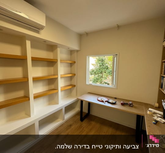 חדר עם מדפים ריקים, שולחן וכלי עבודה לצביעה